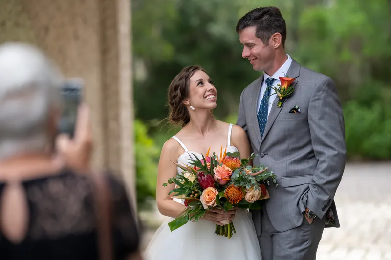 A guest photographs Emma and Kyle as they pose together outside, both smiling during their wedding day.