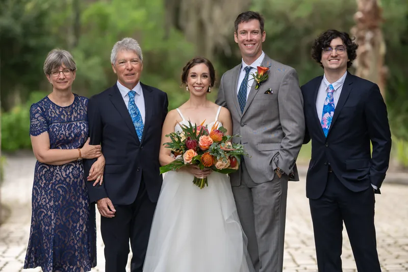 Emma stands between two family members and Kyle for a formal group photo on the brick pathway at Oyster Bay Yacht Club.
