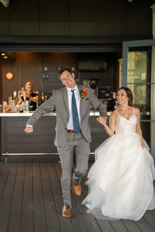Emma and Kyle dance across the wooden deck at Oyster Bay Yacht Club, with guests watching from the bar behind them.