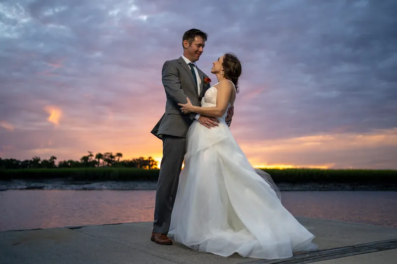 Kyle spins Emma across the deck at Oyster Bay Yacht Club as vibrant sunset colors fill the sky behind them.