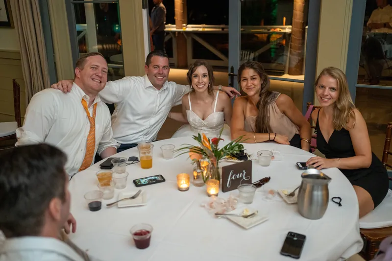 Five guests sit together at a round dinner table, smiling and conversing during the reception.