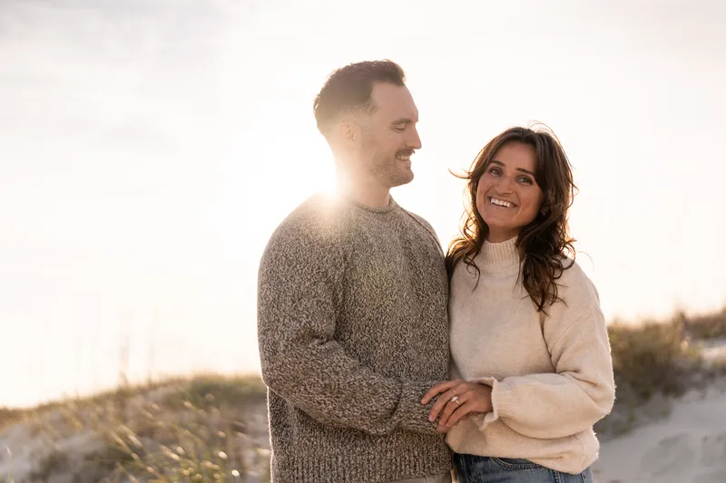 Eric and Anastasia share a joyful moment together during their engagement session, laughing and embracing in beautiful golden hour light.