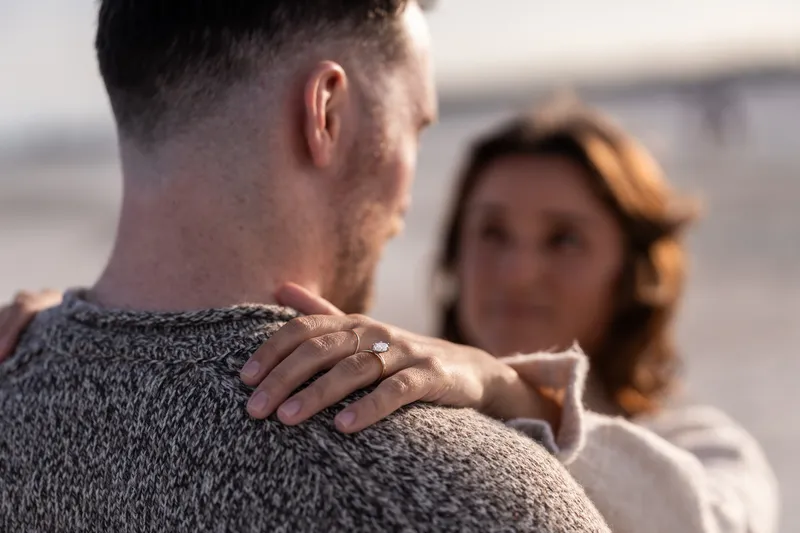 An intimate moment between Eric and Anastasia during their engagement session, with focus on her hand gently resting on his shoulder while wearing her engagement ring.