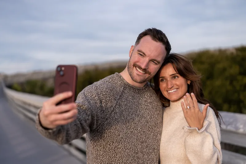 Eric and Anastasia take a sweet selfie together during their engagement session, both beaming with joy as she shows off her engagement ring.