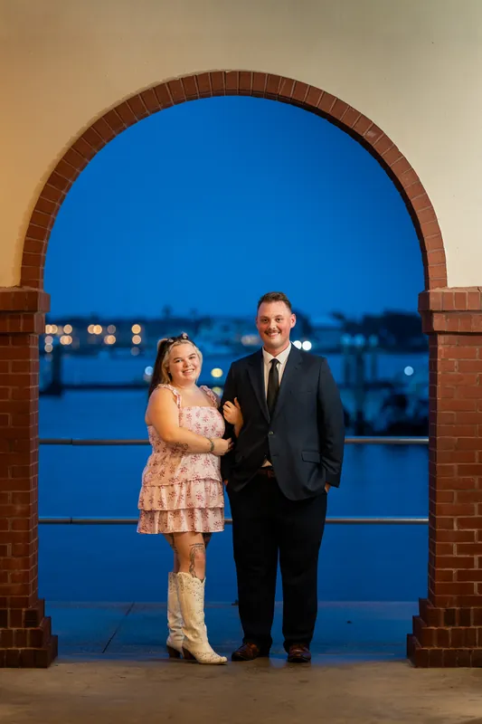 Two people stand together under a brick archway with blue water visible through it at Downtown St Augustine.