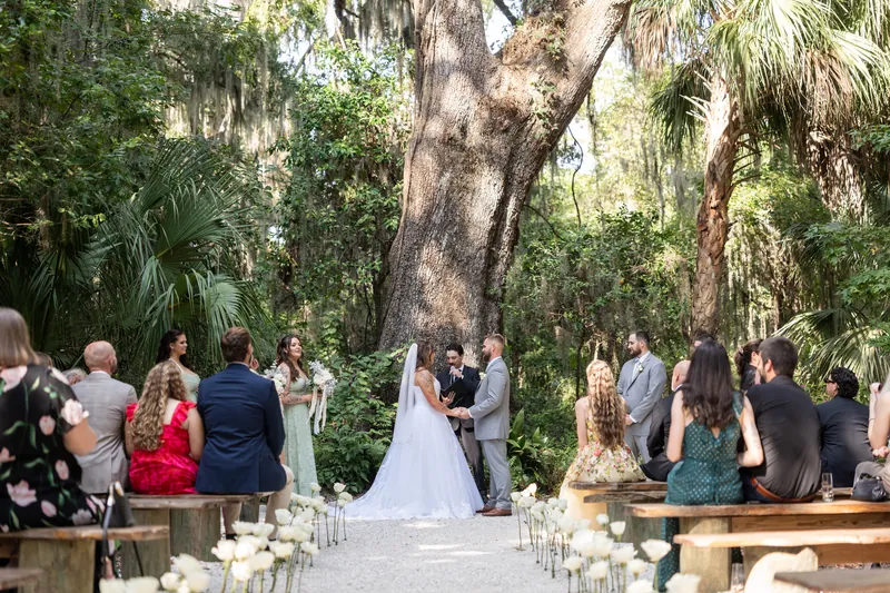 Evelynn and Kevin exchange vows beneath a massive oak tree as their guests line a white aisle through La Venture Grove's lush landscape.