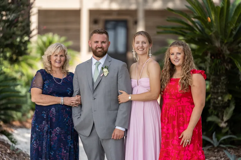 Kevin stands between his mother and two other family members, all dressed formally for the wedding celebration at La Venture Grove.