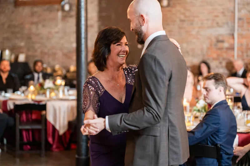 Woman in a sequined dark dress laughing with a man in a gray suit during the reception at Brick and Beam, Jacksonville.
