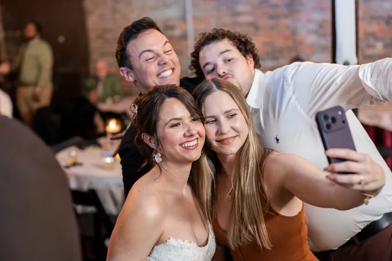 Four guests smile while taking a selfie together at Brick and Beam, Jacksonville.