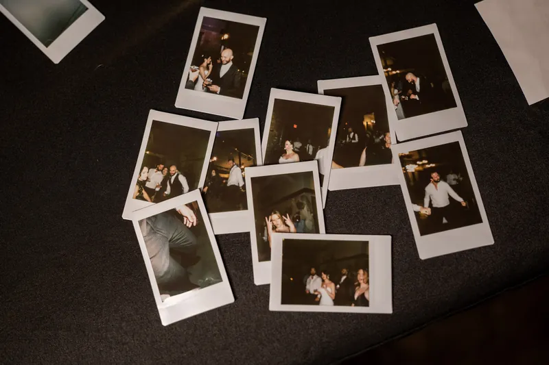 Polaroid photos scattered across a dark surface capture candid moments from the celebration.