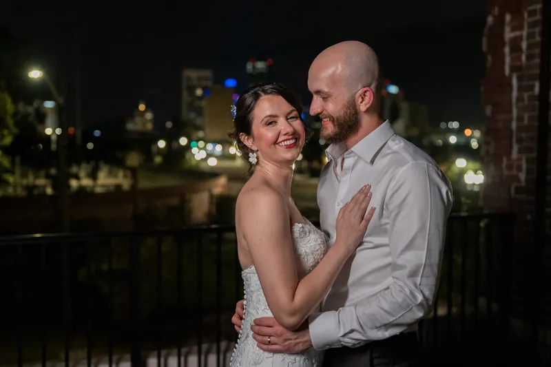 Faith and Christian embrace on an outdoor terrace with the Jacksonville skyline glowing behind them at night.