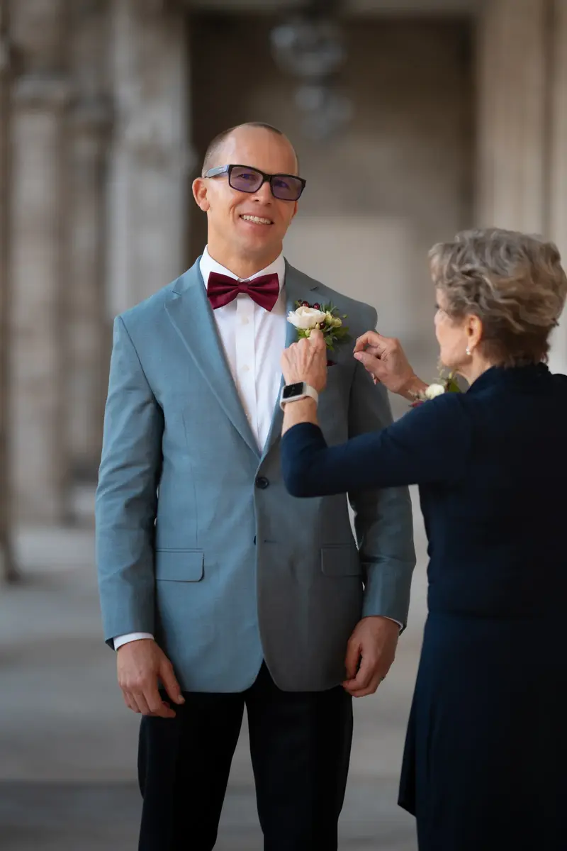 Mother pinning boutonniere on the groom