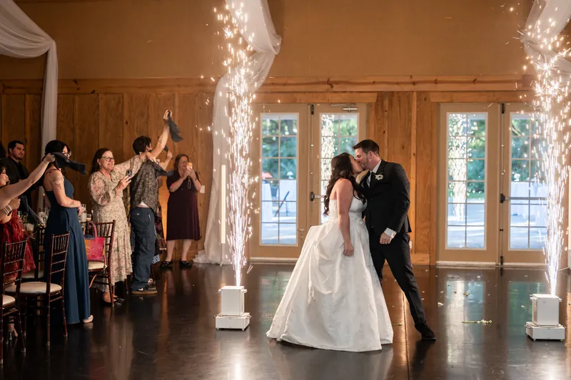 Giselle & Duncan dance under sparkling light installations while guests cheer around them on the dance floor.