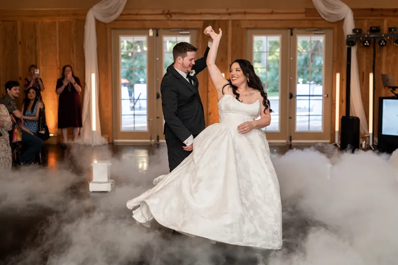 Duncan & Giselle waltz through artificial fog on the dance floor surrounded by seated wedding guests.