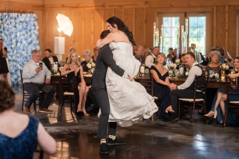 Duncan spins Giselle across the dance floor in her white gown while seated guests applaud nearby.