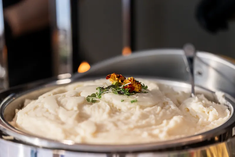 Creamy mashed potatoes topped with herbs and spices served on white plate.