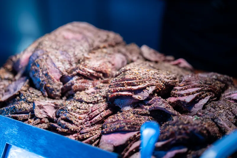 Sliced medium-rare steak with salt crust on blue serving platter.