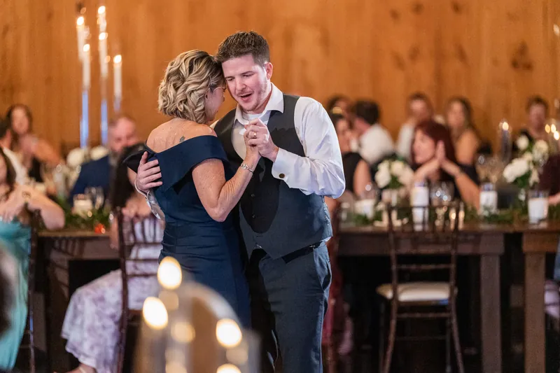 Giselle and Duncan embrace while slow dancing, with white candles and floral arrangements visible at the head table behind them.