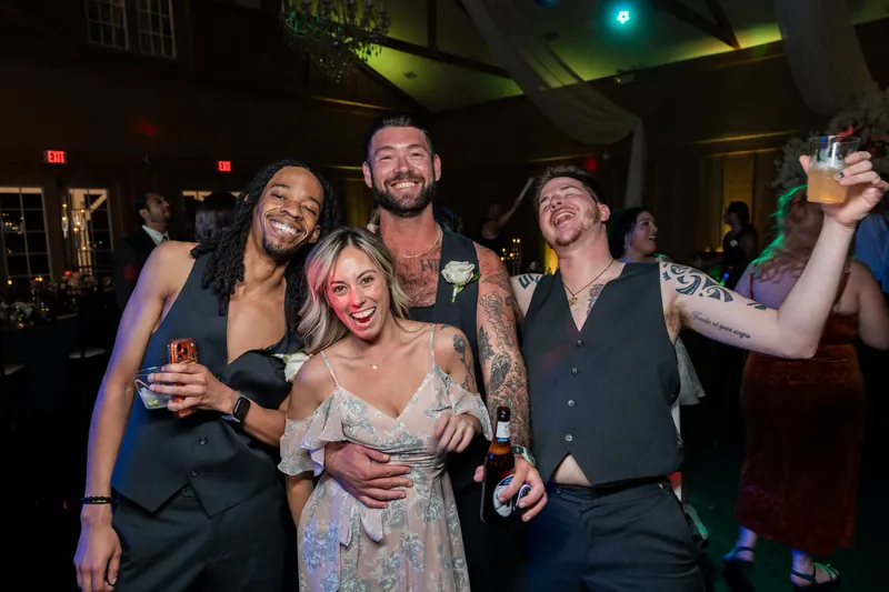 Duncan and Giselle pose with friends at the reception, holding drinks and smiling.