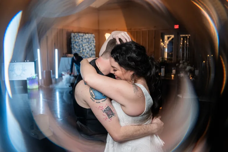 Couple embracing under decorative spherical light installation at wedding venue.
