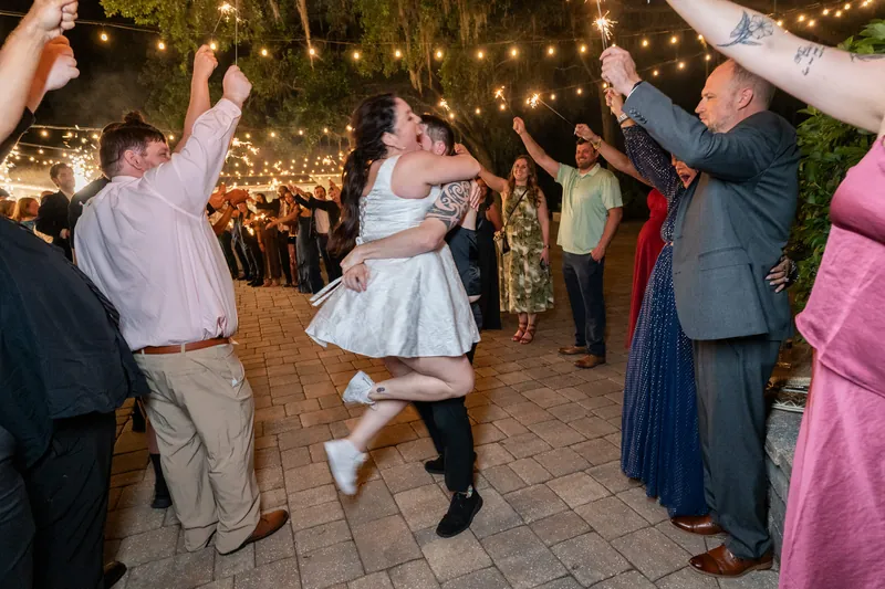 Giselle & Duncan dance together as guests clap under lit tree canopy.