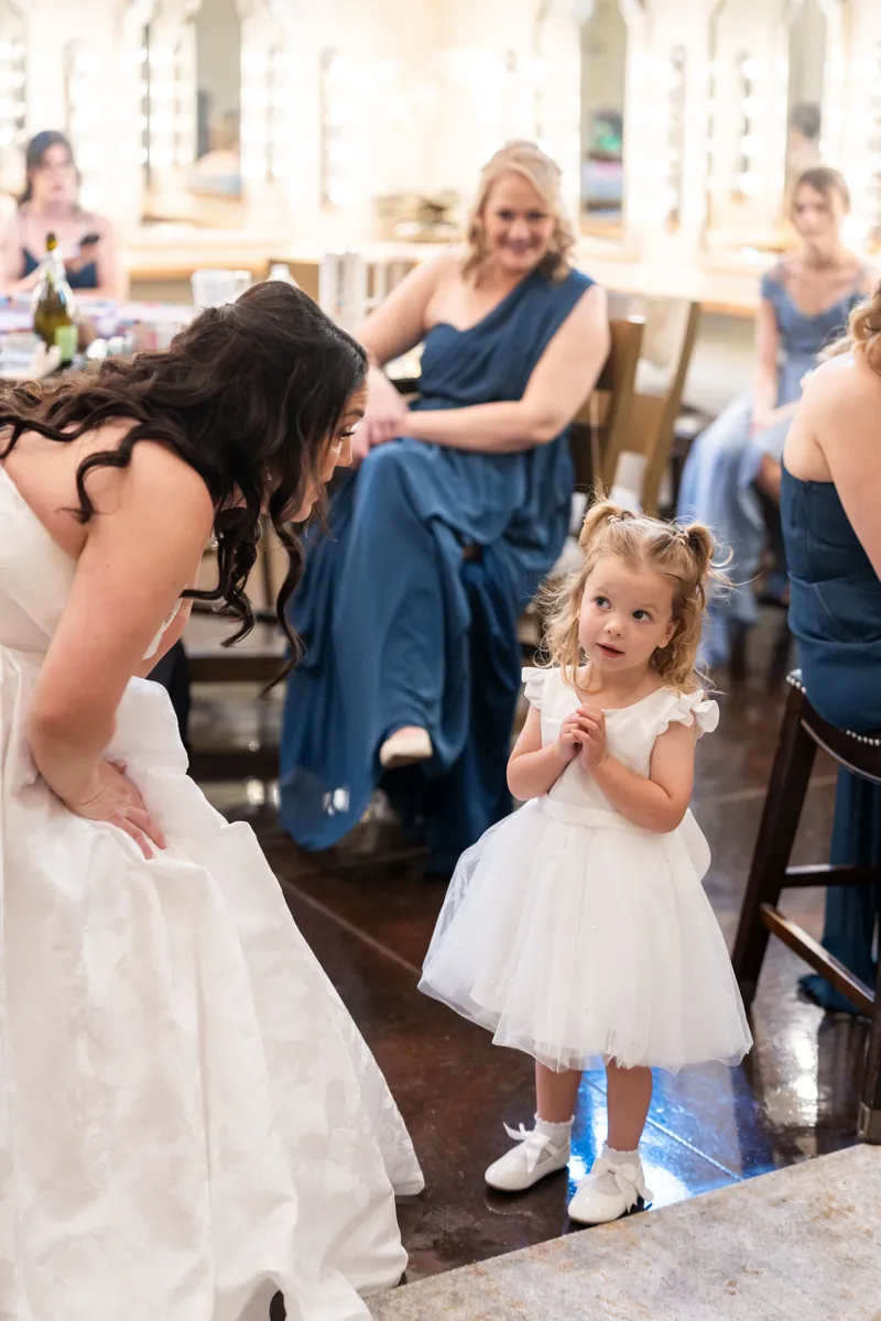 Giselle bends down to greet a flower girl in a white dress during the ceremony.