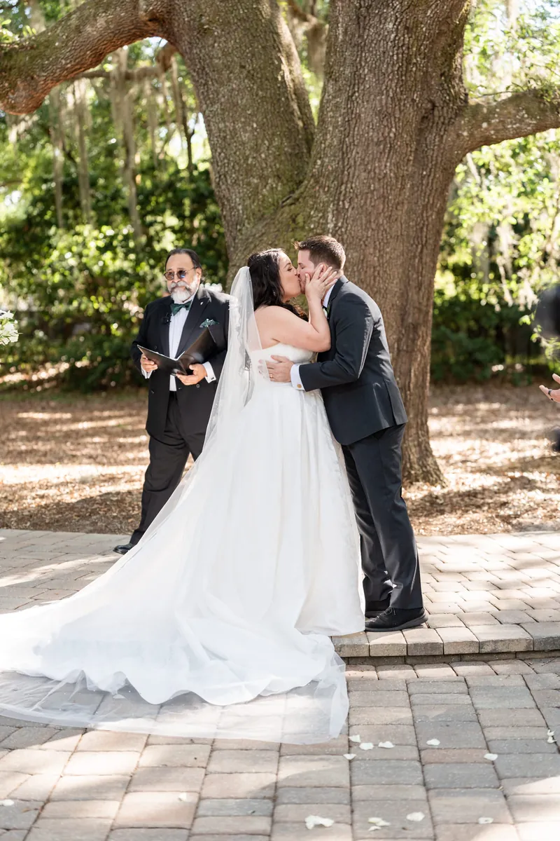 Giselle & Duncan exchange vows beneath a sprawling oak tree with their officiant during their ceremony.