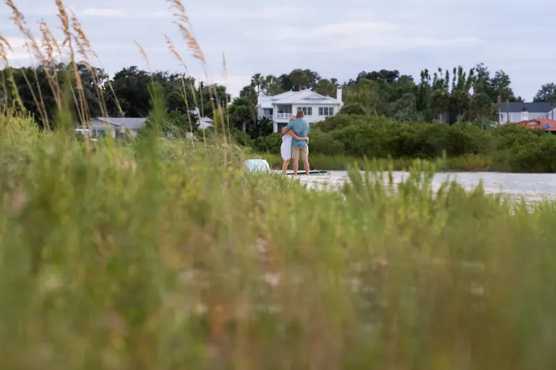 Couple embracing on sandbar viewed through sea oats