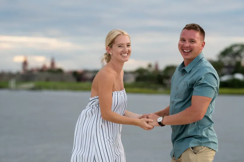 Couple laughing together holding hands by water