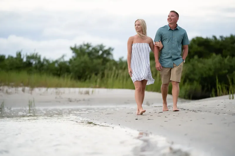 Couple walking arm in arm along sandbar