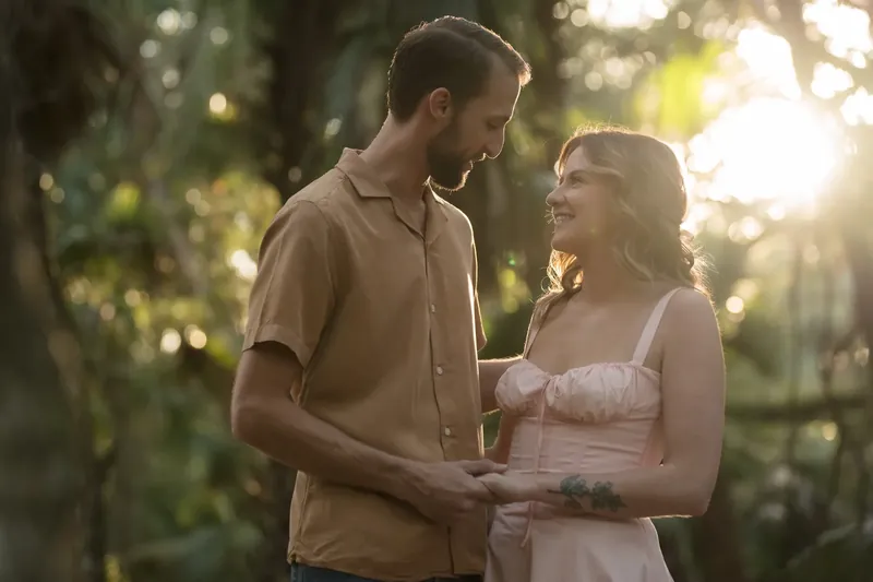 Helen and Saje embracing during golden hour under the oaks at Washington Oaks