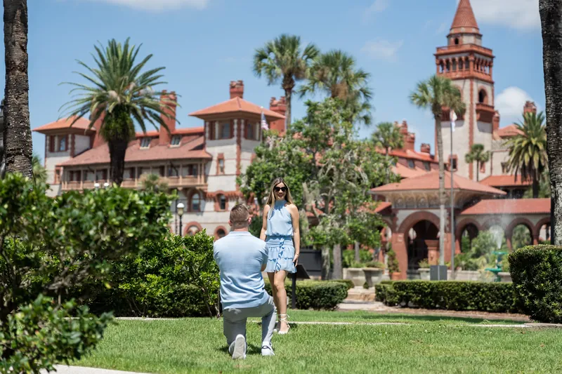 Jakub and Josy embrace on the lawn with the historic mansion and palm trees visible behind them.