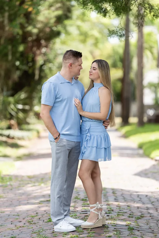 The couple walks hand-in-hand along a brick pathway shaded by tall oak trees in Downtown St Augustine.
