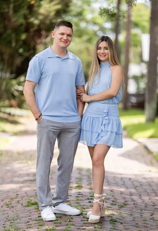 Jakub and Josy stand facing each other on a brick street lined with massive oak trees in Downtown St Augustine.