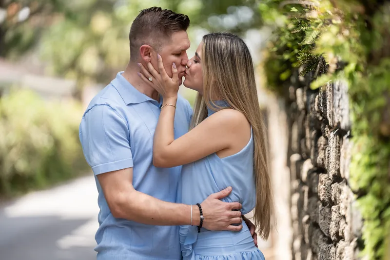Jakub and Josy kiss against a vine-covered stone wall on a quiet street in Downtown St Augustine.