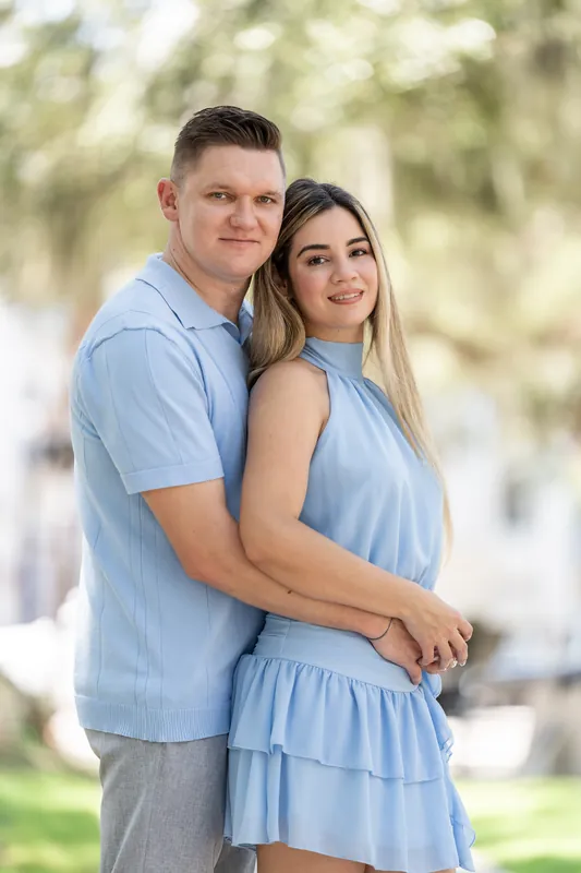 Jakub and Josy embrace beneath moss-draped oak trees in Downtown St Augustine, both wearing light blue outfits.