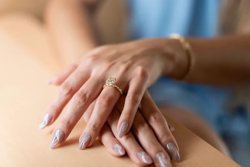A diamond engagement ring sparkles on Josy's hand as she rests it on Jakub's shoulder.