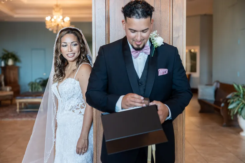 Rick signs the marriage license while Janet stands beside him in her lace wedding dress and veil.