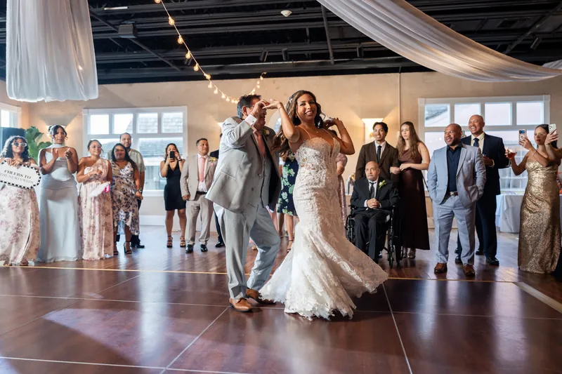 Rick spins Janet across the dance floor in her lace gown while wedding guests watch from all sides.
