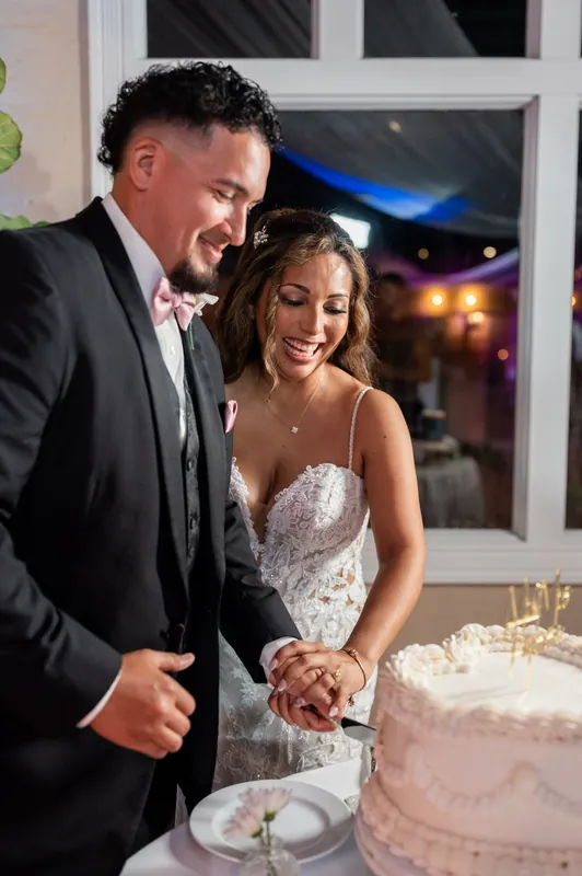 Rick and Janet cut their tiered wedding cake together, both smiling as they hold the knife.