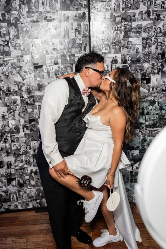 Rick kisses Janet against a black-and-white photo backdrop at The White Room during their reception.