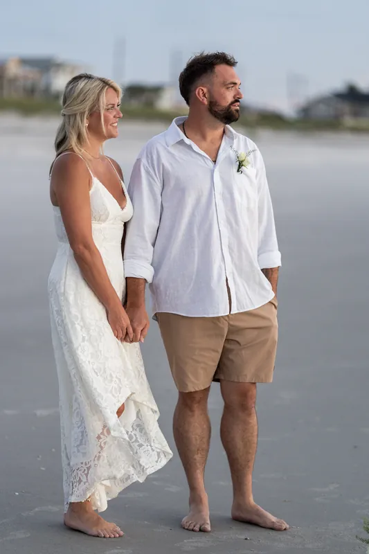 Brandon and Jarah stand together on the wet sand at Vilano Beach, holding hands and gazing toward the horizon.
