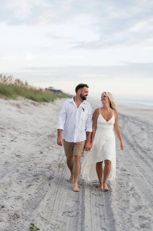 The couple walks hand-in-hand down the shoreline in bare feet, Brandon in a light blue shirt and Jarah in white.