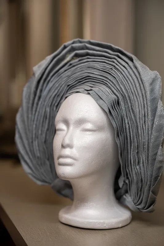 A mannequin head wears a textured gray head wrap displayed indoors.