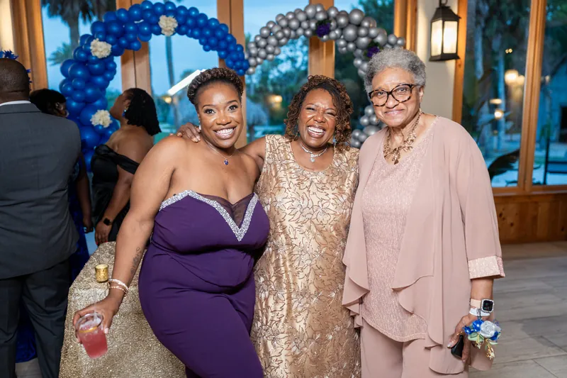 Three women smile at the reception: Jazzalynn in a strapless blue dress, a guest in a gold sequin gown, and an older woman