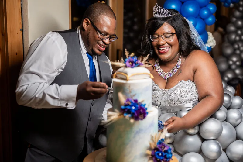 Jazzalynn and Hakeem cut their tiered wedding cake decorated with blue and purple flowers at Fountain of Youth Archaeological