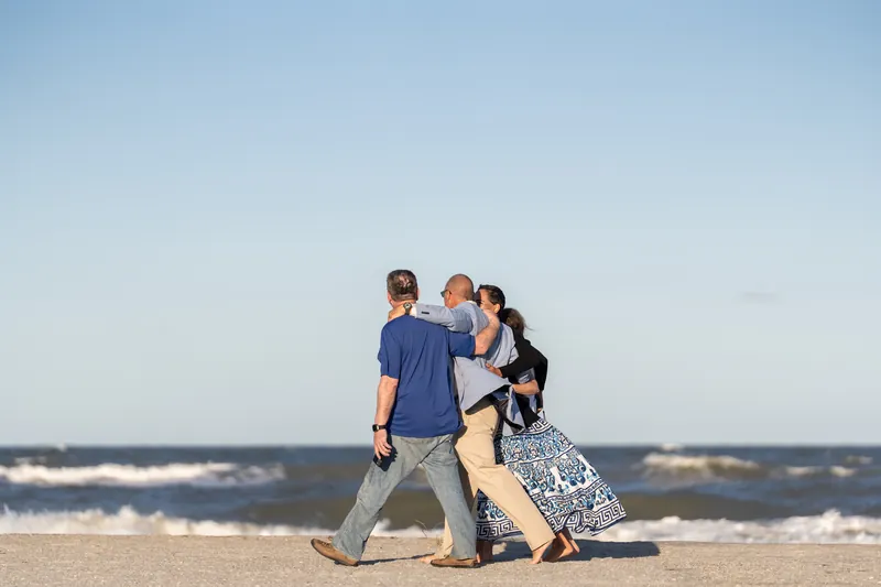 Two people stand together on the sand at St. Augustine Beach as a third person approaches from behind.