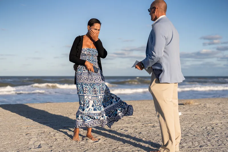 Jeff and Ella stand on the beach at St. Augustine Beach with waves rolling behind them during their proposal.