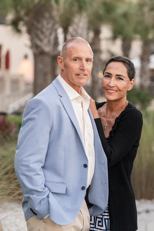 Two people pose together on a quiet street lined with historic buildings and palm trees at St. Augustine Beach.