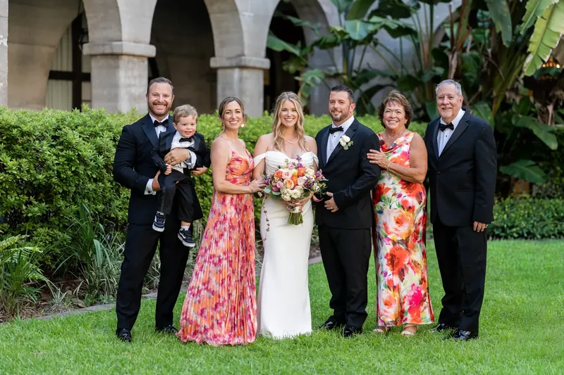 Seven family members, including Jenna and Russell at center, pose formally on the courtyard lawn.